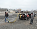 Douglas Tait and Dustin McIver work to clean the lines for the asphalt crack sealer. (U.S. Air Force photo / W. Eugene Barnett Jr.)  