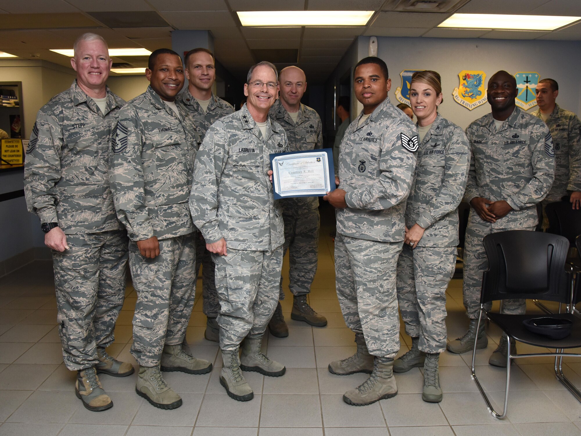 Maj. Gen. Bob Labrutta, 2nd Air Force commander and Staff Sgt. Courtney Hill, 81st Security Forces Squadron pass and ID NCO in charge, poses for a photo with base leadership during a Stripes for Exceptional Performers promotion ceremony at the visitors center March 30, 2017, on Keesler Air Force Base, Miss. Hill was STEP promoted to the rank of technical sergeant. In the past year, Hill oversaw the issue of 20,000 passes and coordinated entry for multiple base events. His hard work and dedication was acknowledged when he won 81st Mission Support Group NCO of the year for 2016. (U.S. Air Force photo by Kemberly Groue)