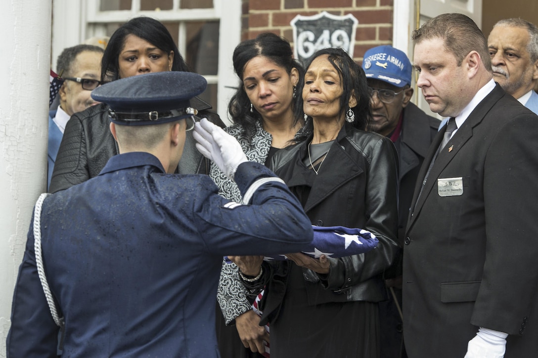 Air Force Airman 1st Class Joshua Ashe salutes after the presentation of an American flag to Joan Harrison, daughter of Maj. John L. Harrison Jr., a Tuskegee Airman, during his funeral service at the Navy Yard in Philadelphia, March 31, 2017. Ashe is a member of the Dover Air Force Base Honor Guard. Air Force photo by Senior Airman Zachary Cacicia