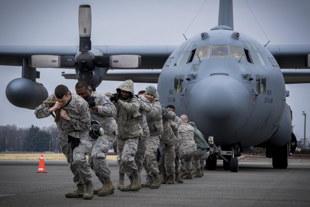 Members of the 374th Aircraft Maintenance Squadron pull a C-130H Hercules down the runway during the 374th Maintenance Group Wrenchbender Rodeo March 31, 2017, at Yokota Air Base, Japan. Teams from various maintenance squadrons competed against each other in nine events including: 4-man push-ups, vehicle push, blindfolded toolbox buildup, maintenance relay, tow bar obstacle course, leadership tool identification, chock hold, Self-Aid and Buddy Care relay and finished with a C-130 pull. (U.S. Air Force photo by Airman 1st Class Donald Hudson)