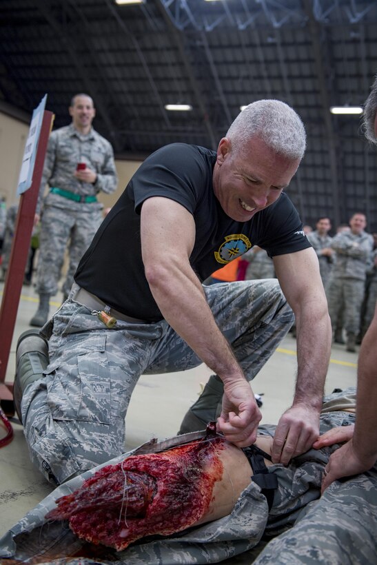 Lt. Col. Bernabe F. Whitfield, 374th Maintenance Group deputy commander, secures a tourniquet on a practice doll as part of the Self-Aid and Buddy Care race during the 374th Maintenance Group Wrenchbender Rodeo March 31, 2017, at Yokota Air Base, Japan. The MX Rodeo is a morale event and allows for friendly competition between the various maintenance squadrons on base. (U.S. Air Force photo by Airman 1st Class Donald Hudson)