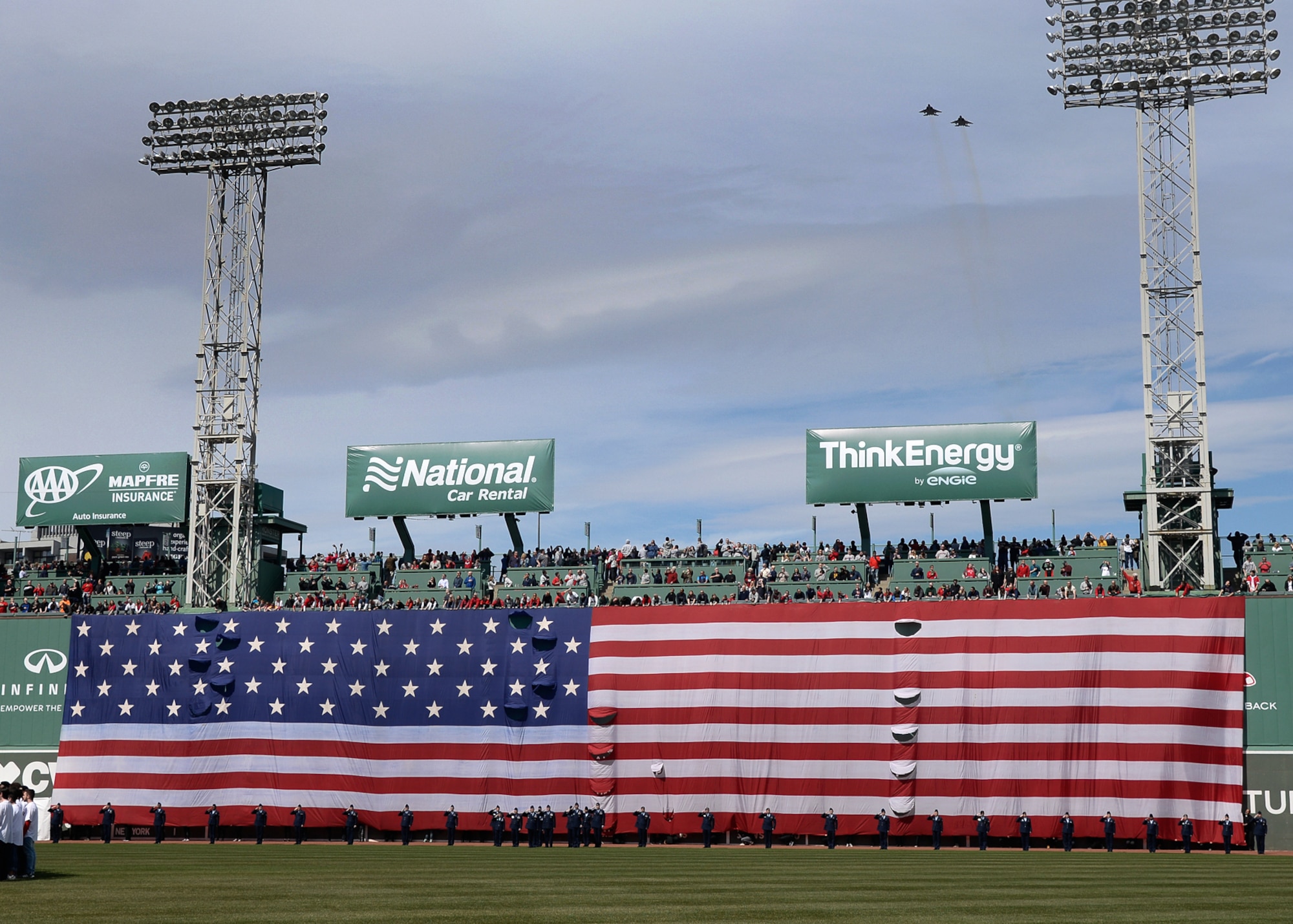 Airmen salute during the playing of the national anthem at Fenway Park for the Boston Red Sox opening day festivities April 3, while F-15s from the 104th Fighter Wing from Barnes Air National Guard Base, Mass., perform a fly over. Hanscom AFB has a long-standing community partnership with the Red Sox organization. (U.S. Air Force photo by Mark Herlihy)