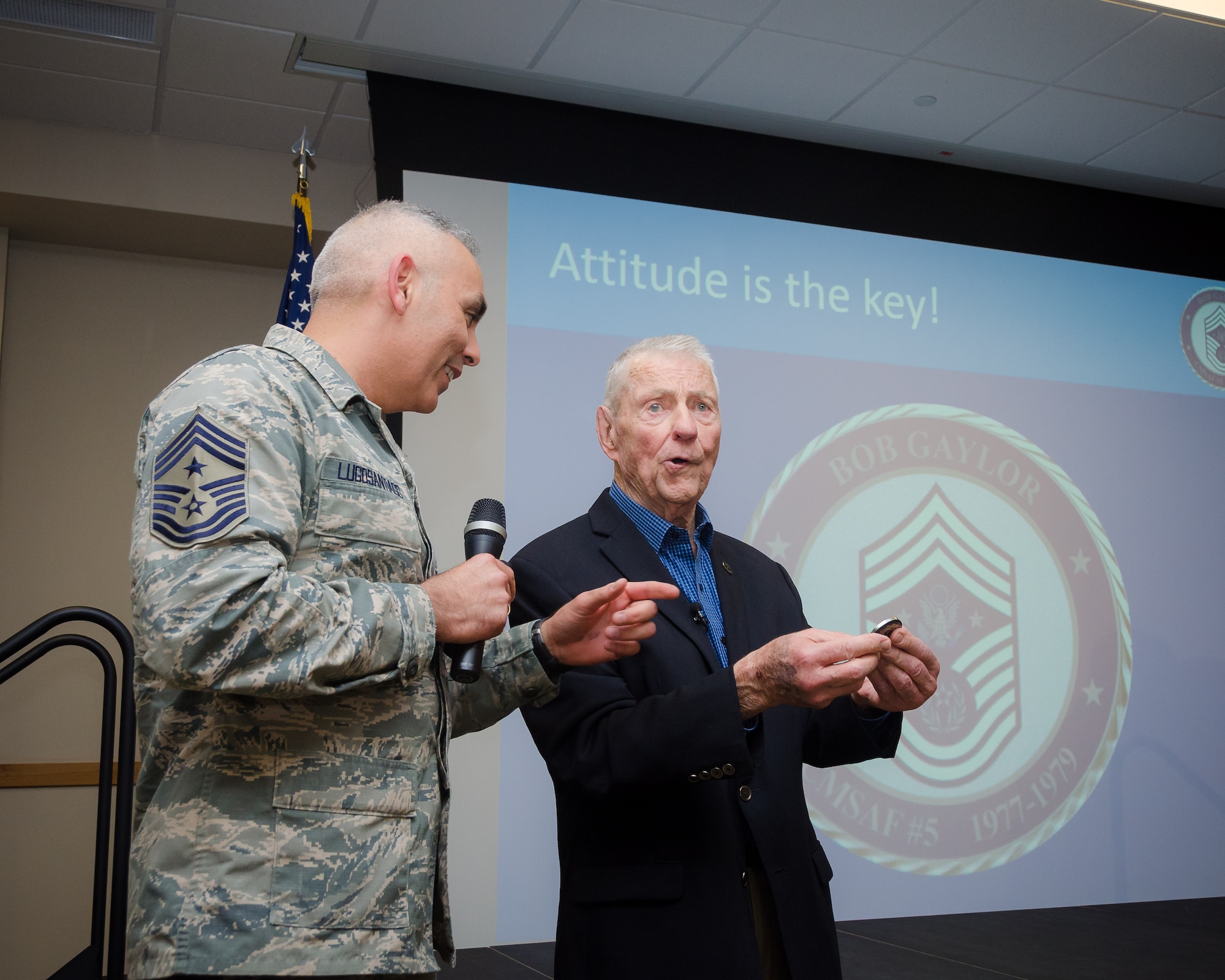 Chief Master Sgt. Jose A. LugoSantiago, command chief of the Air Force Installation and Mission Support Center, coins retired Chief Master Sgt. Robert Gaylor during his visit with Airmen at Joint Base San Antonio-Lackland, March 30, 2017. Gaylor was the fifth Chief Master Sergeant of the Air Force serving from 1977-1979. Now at age 86, Gaylor continues to visit Airmen across the Air Force. (U.S. Air Force photo by Malcolm McClendon)