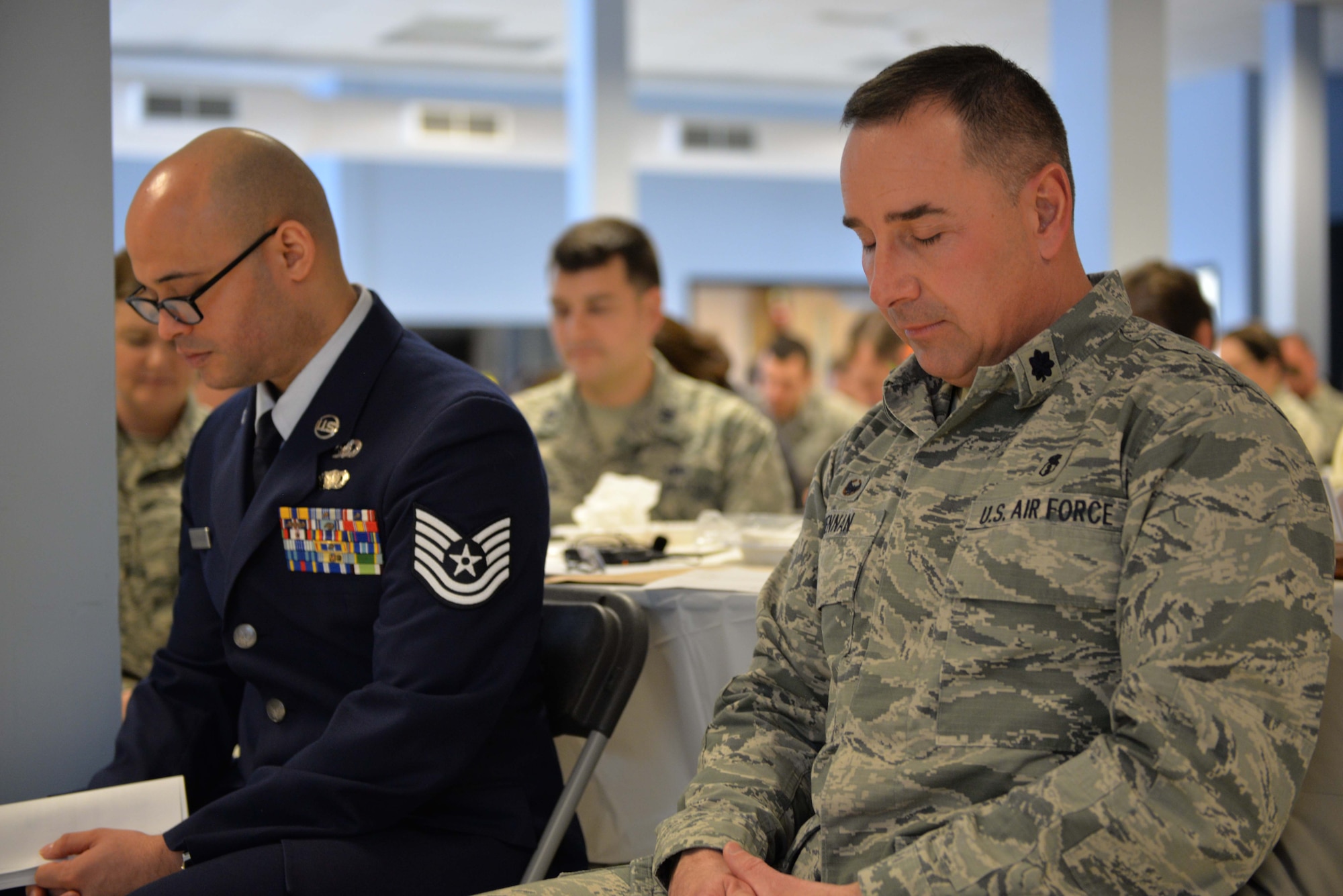 From the left, Tech. Sgt. Siddartha Sosa Rodriguez, a member of the 157th Air Refueling Wing Chaplin’s Corps, and Lt. Col. Fred Brennan, 157th Medical Group commander, bow their heads during a prayer for the nation at the Commanders Annual Prayer Breakfast, April 2, 2017, Pease Air National Guard Base, N.H.(N.H. Air National Guard Photo by Senior Airman  Ashlyn J. Correia)