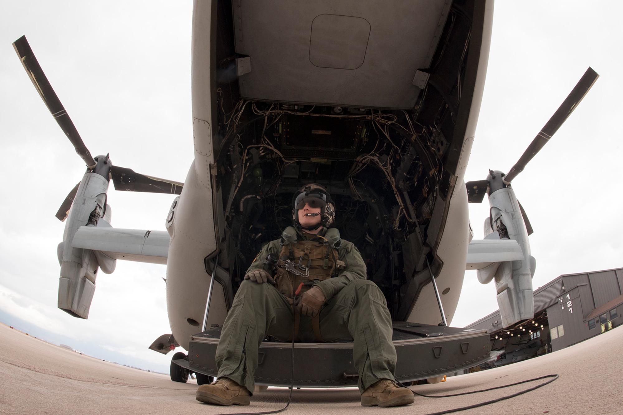 PETERSON AIR FORCE BASE, Colo. — Marine Sgt. Tyler Brereton, Marine Medium Tiltrotor Squadron 261 (VMM-261) crew chief, sits on the tail ramp of a V-22 Osprey aircraft before conducting flight operations at Peterson Air Force Base, Colo., March 28, 2017. VMM-261 is based at Marine Corps Air Station New River, S.C., and is at Peterson AFB conducting high altitude training. (U.S. Air Force photo by Steve Kotecki)