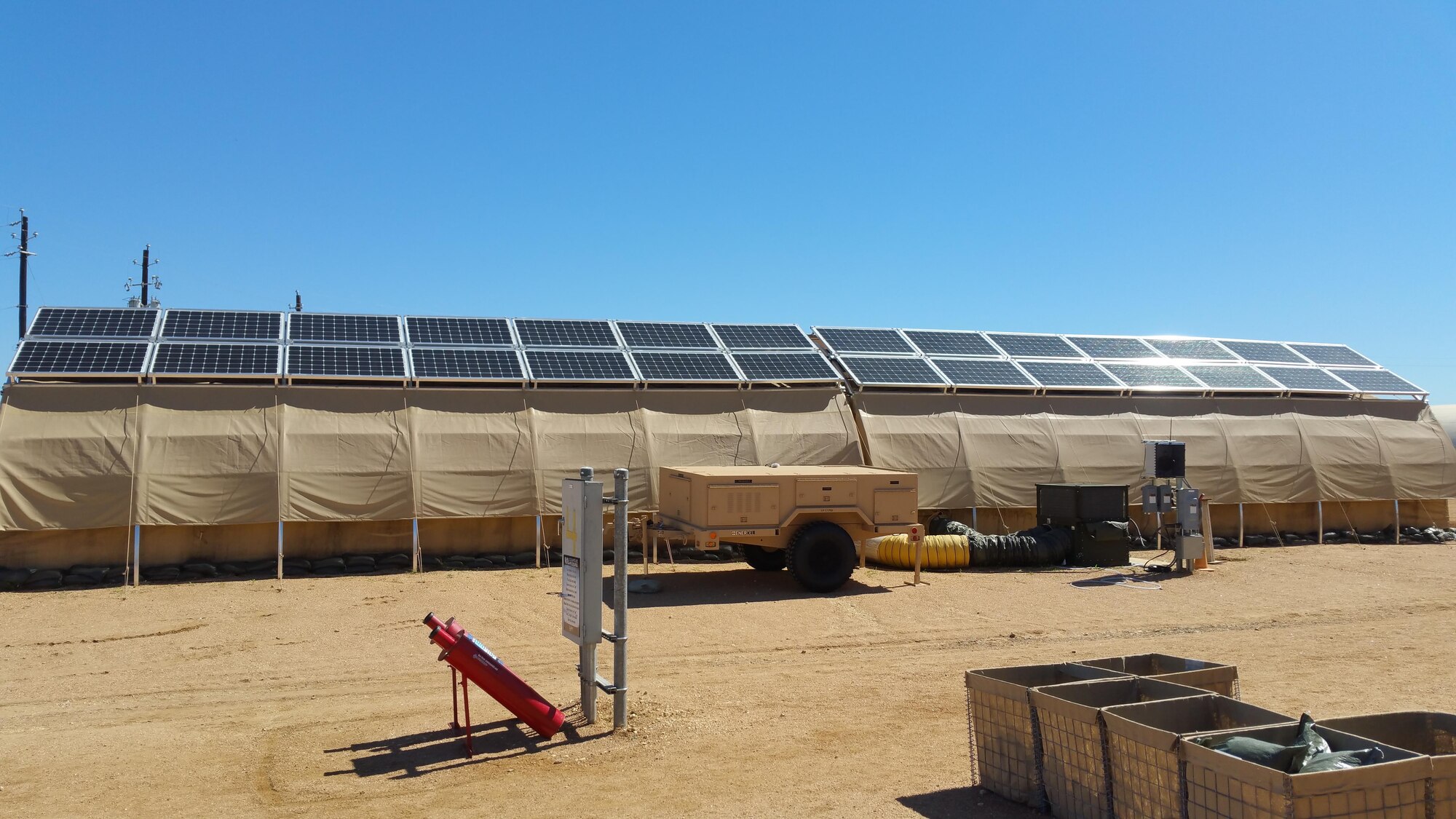 Part of AFRL's Forward Operating Base of the Future demonstration is one complete expeditionary microgrid system at Basic Expeditionary Airmen Skills Training (BEAST), Lackland AFB, San Antonio, Texas. Monocrystalline silicon solar panels are placed on top of each tent for energy production. A trailer (center) holds the hardware, software and lithium ion batteries that form the smart grid and provide energy backup should the grid fail. The project evaluates energy reduction technologies such as shelter insulation and efficient HVACs. (U.S. Air Force photo/Jason Goins)