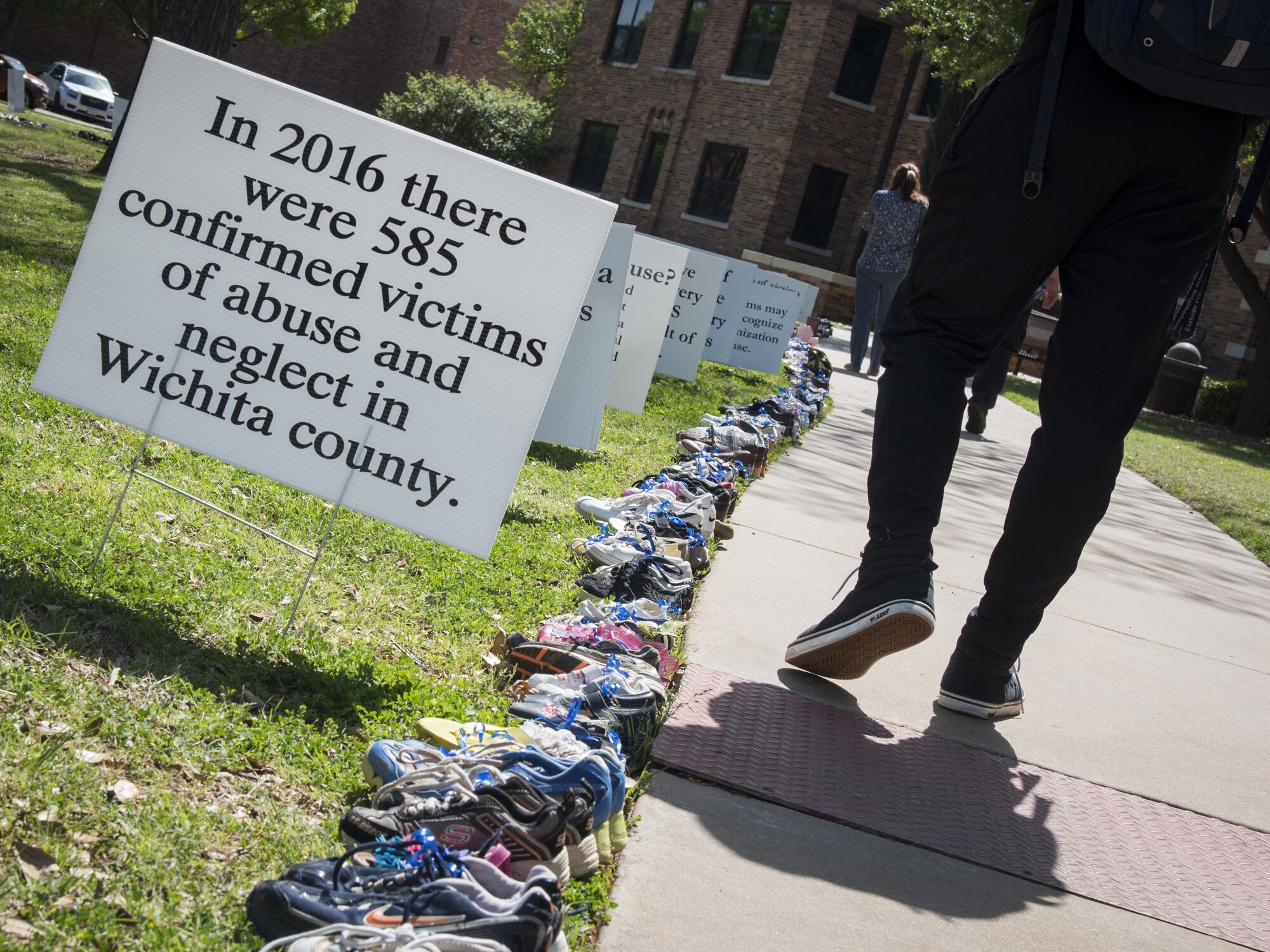 A student from Midwestern State University participates in the annual Walk of Knowledge April 4, 2017, held at MSU’s Sunwatcher Plaza. Participants walked the sidewalk lined with educational signs and 585 pairs of children’s shoes representing each case of confirmed child abuse in Wichita County during 2016. (U.S. Air Force photo by 2nd Lt. Jacqueline Jastrzebski)