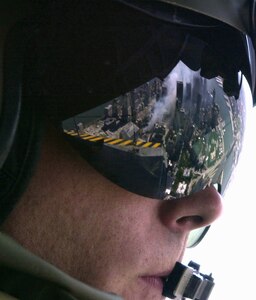 Smoldering fires of the World Trade Center are reflected in the visor of a United States Air Force MH-53M helicopter flight engineer days after the September 11th terrorist attack on the United States. This photograph was provided by the 1st Combat Camera Squadron to showcase some high-profile events that they have covered. This photograph was provided by the 1st Combat Camera Squadron to showcase
world events they have documented throughout the past 25 years.