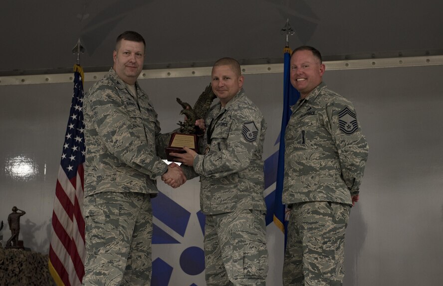 Col. Shane Barrett, 23d Maintenance Group commander, left, presents the Outstanding Armament Manager of the Year award to Master Sgt. Joseph Holdcroft, 23d Equipment Maintenance Squadron weapons standardization superintendent, center, during the 2016 Maintenance Professional of the Year banquet, March 31, 2017, at Moody Air Force Base, Ga. During the event, the 23d MXG honored 28 Airmen for their exceptional service.  (U.S. Air Force photo by Airman 1st Class Lauren M. Sprunk)