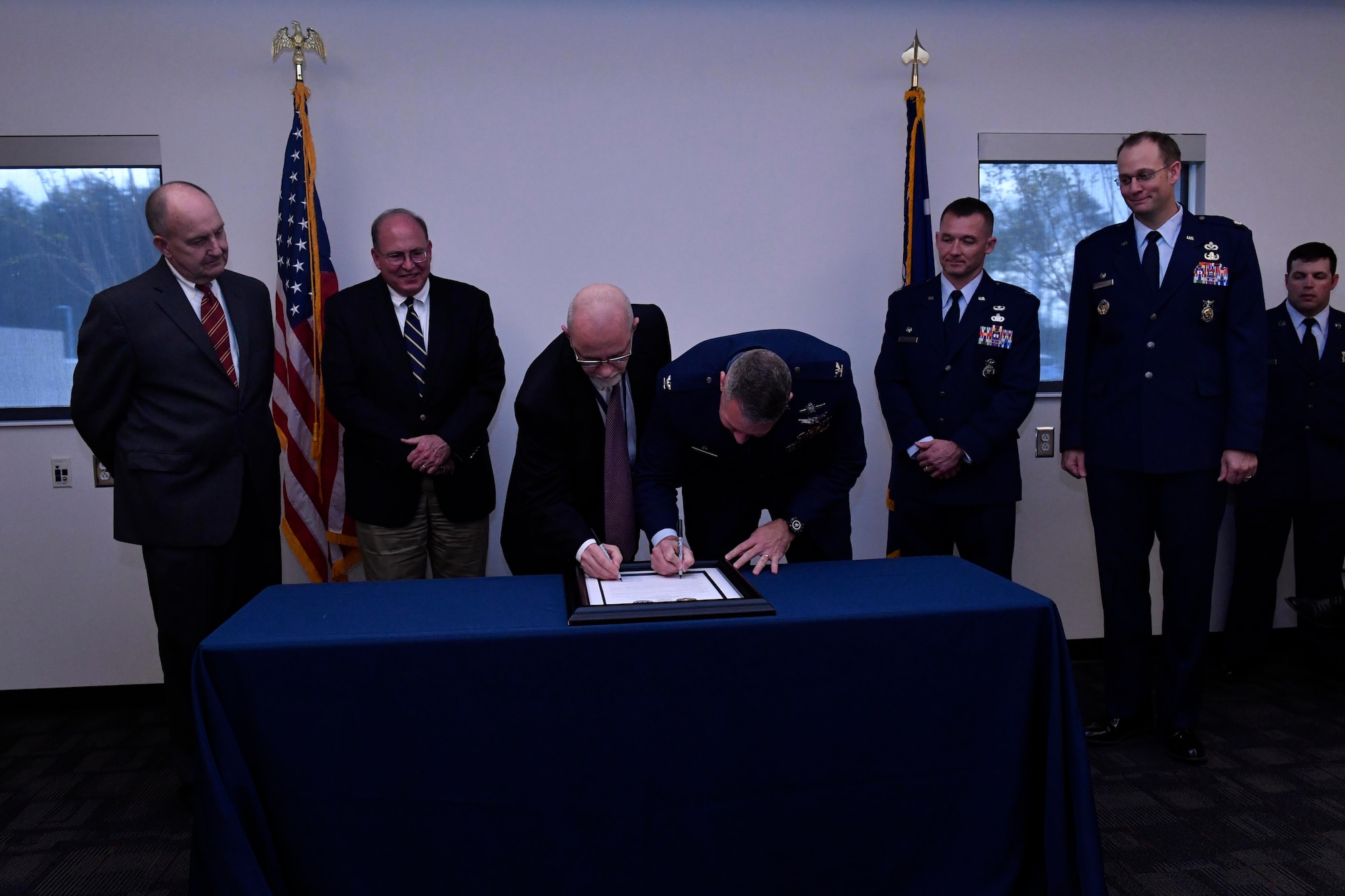 Col. Rob Lyman, the Joint Base Charleston commander, signs a memorandum of agreement with Keith Bustraan, the Charleston County administrator, at the Charleston County Consolidated 911 Center, March 30, 2017. The Enhanced 911 initiative combines the call centers for the 628th Security Forces Squadron and fire department with the Charleston County Consolidated 911 Center, ultimately shortening response times, saving money and saving lives. (U.S. Air Force photo/Airman 1st Class Megan Munoz)