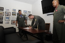 The 9th Attack Squadron commander signs the Reaper Armistice Agreement in the presence of the 6th Attack Squadron commander, and the 29th Attack Squadron commander, March 31, 2017, at Holloman Air Force Base, N.M. The Reaper Armistice Agreement is an esprit de corps arrangement between the three squadrons that marks the neutral time when the capture of non-mission essential belongings from a different attack squadron, in the name of competitive spirit, isn’t allowed at Holloman AFB. (U.S. Air Force photo by Master Sgt. Matthew McGovern)