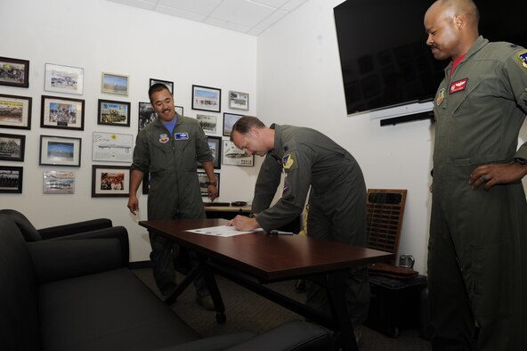 The 9th Attack Squadron commander signs the Reaper Armistice Agreement in the presence of the 6th Attack Squadron commander, and the 29th Attack Squadron commander, March 31, 2017, at Holloman Air Force Base, N.M. The Reaper Armistice Agreement is an esprit de corps arrangement between the three squadrons that marks the neutral time when the capture of non-mission essential belongings from a different attack squadron, in the name of competitive spirit, isn’t allowed at Holloman AFB. (U.S. Air Force photo by Master Sgt. Matthew McGovern)