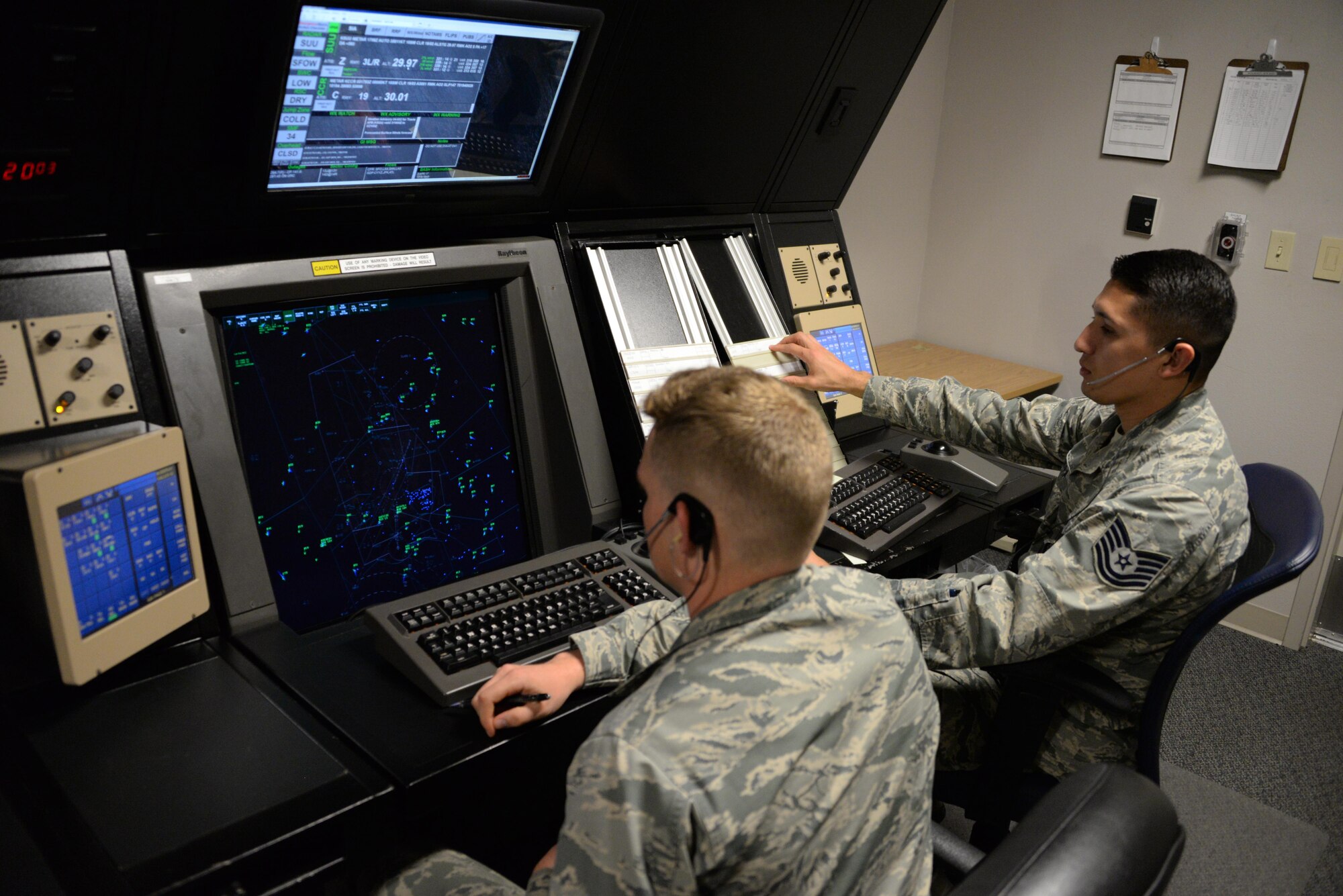 Airman Benjamin Cobb (Left) and Tech. Sgt. Ruben Rivera (Right), both members of the 60th Operations Support Squadron, monitor air traffic over Travis Air Force Base, Calif., inside the Travis Radar Approach Control facility April 3, 2017. Travis air traffic controllers monitor an average of 367 aircraft daily. (U.S. Air Force photo/Tech. Sgt. James Hodgman/Released)
