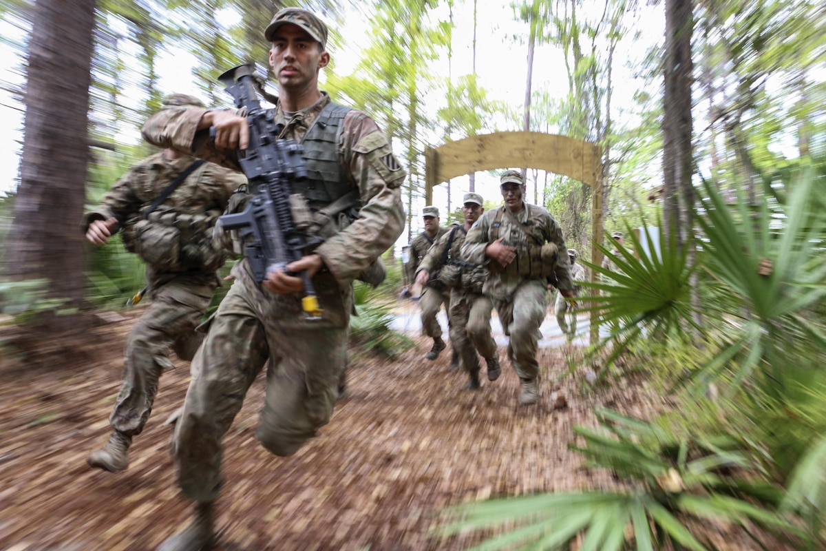 Soldiers carry weapons as they race through trees and plants.