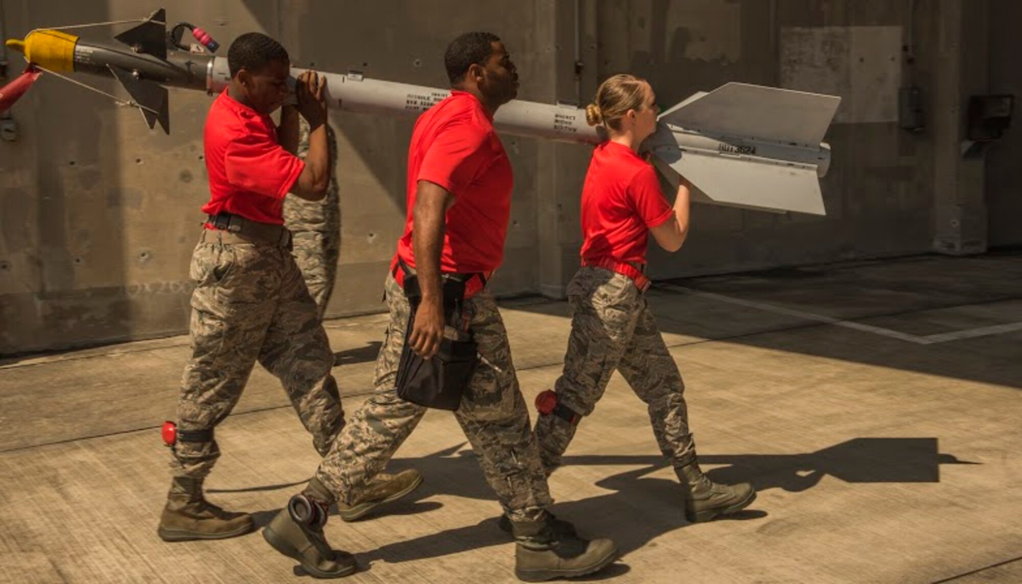 A U.S. Air Force weapons load crew team from the 67th Aircraft Maintenance Unit carry an AIM-9L/M Sidewinder missile to an F-15 Eagle fighter aircraft during a quarterly weapons load competition April 3, 2017, at Kadena Air Base, Japan. The competition pitted two load crews against each other to evaluate who could prepare the aircraft for combat the fastest and with the fewest procedural errors. (U.S. Air Force photo by Senior Airman Nick Emerick /Released)
