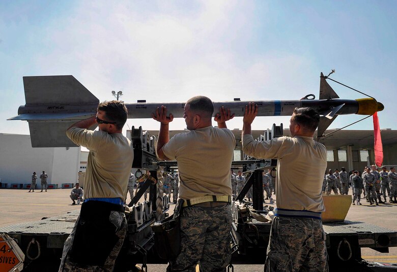 A U.S. Air Force weapons load crew team from the 44th Aircraft Maintenance Unit carry an AIM-9L/M Sidewinder missile to an F-15 Eagle fighter aircraft during a quarterly weapons load competition April 3, 2017, at Kadena Air Base, Japan. The competition pitted two load crews against each other to evaluate who could prepare the aircraft for combat the fastest and with the fewest procedural errors. (U.S. Air Force photo by Naoto Anazawa/Released)