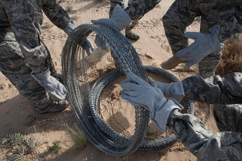 Airmen assigned to the 407th Expeditionary Security Forces Squadron lay concertina wire along installation defense points to increase base security at the 407th Air Expeditionary Group, March 20, 2017. The security forces squadron is responsible for security of U.S. Air Force, Marine, coalition and host-nation assets.  (U.S. Air Force photo/Master Sgt. Benjamin Wilson)(Released)