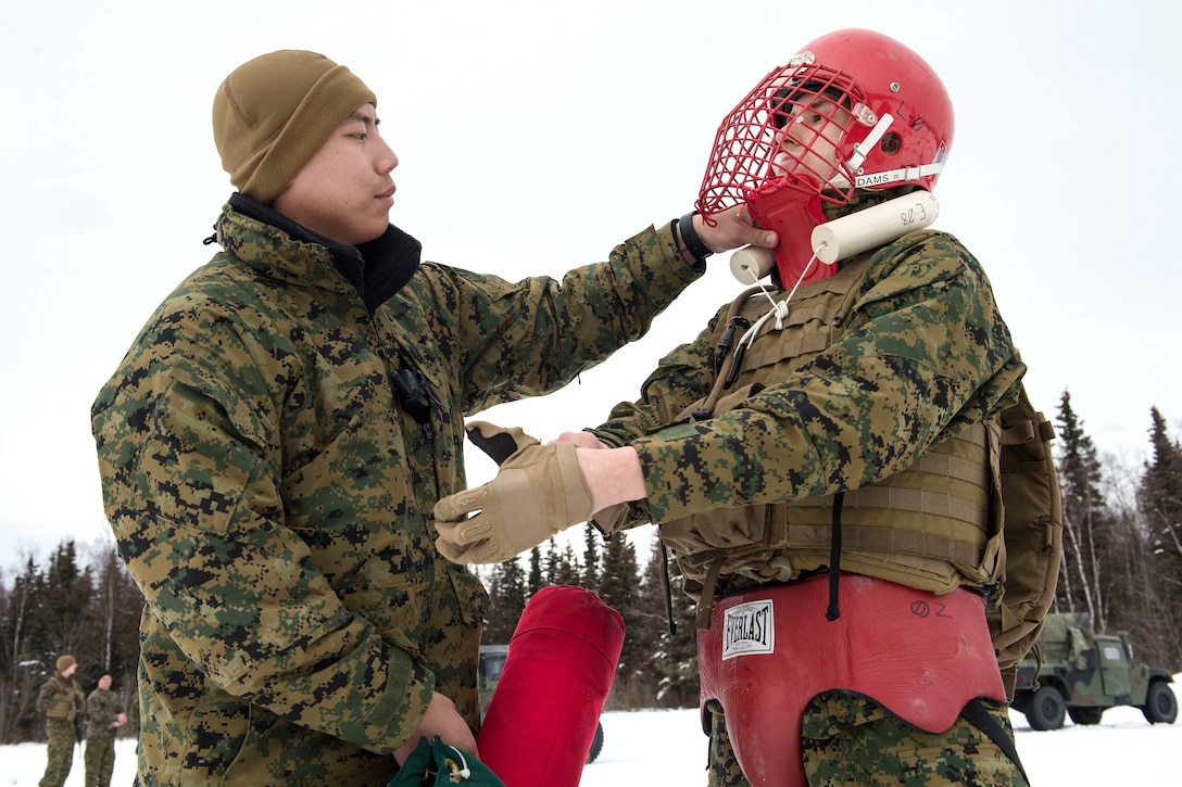 Marine Corps Sgt. Steven Lee, left, assists Cpl. Nick Ruthruff as he puts on protective gear before participating in pugil stick training at Joint Base Elmendorf-Richardson, Alaska, April 2, 2017. Lee and Ruthruff are military police officers assigned to Detachment Delta, 4th Law Enforcement Battalion. Pugil stick bouts are used to simulate close quarters combat and build proficiency of rifle bayonet techniques.  Air Force photo by Alejandro Pena