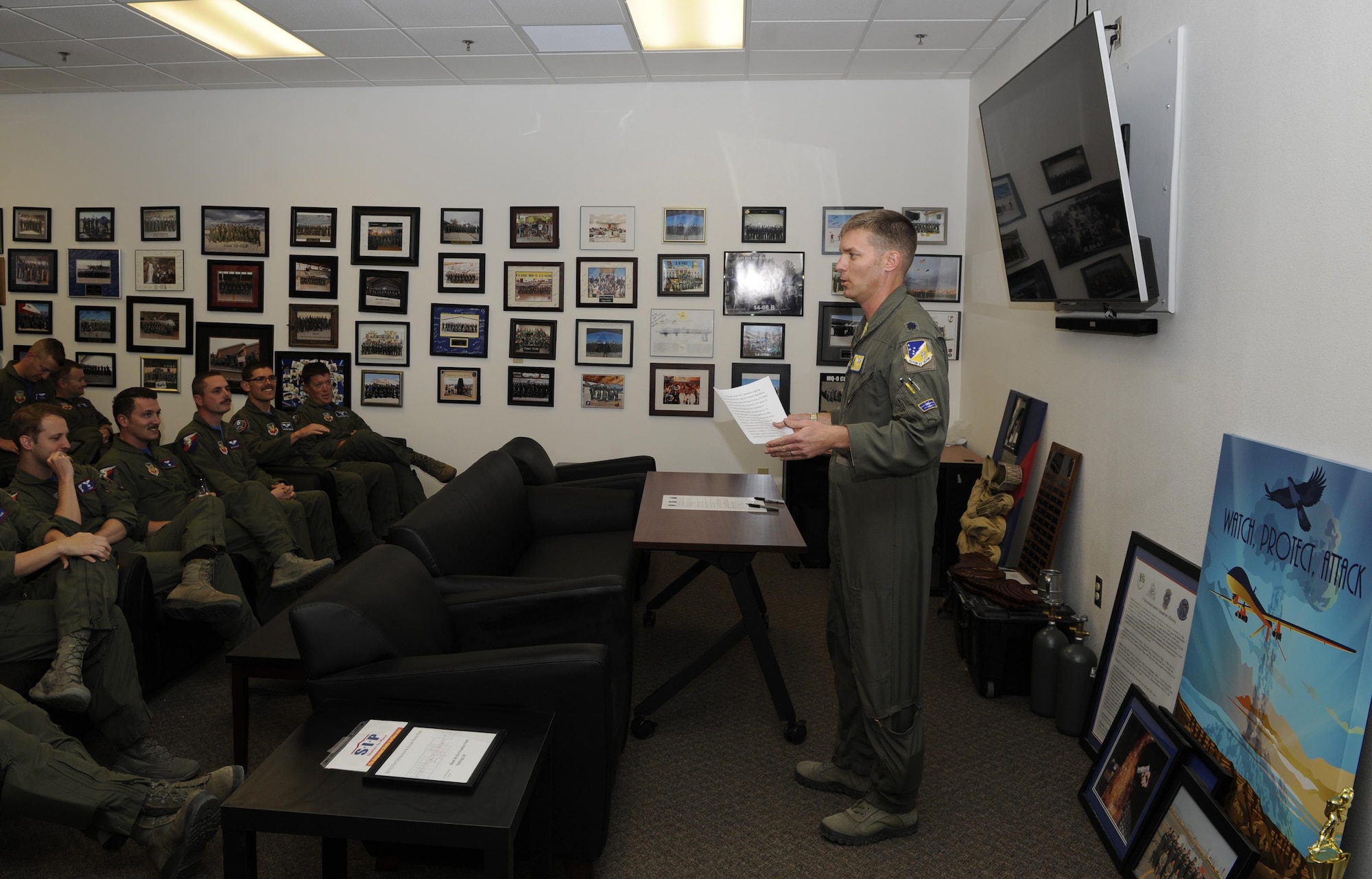 The 16th Training Squadron commander, describes the Reaper Armistice Agreement to Airmen from the 6th, 29th, and 9th Attack Squadrons before the commanders of those squadrons sign the document. The Reaper Armistice Agreement is an esprit de corps arrangement between the three squadrons that marks the neutral time when the capture of non-mission essential belongings from a different attack squadron, in the name of competitive spirit, isn’t allowed at Holloman AFB. The items captured during the spirit missions, positioned behind the commander, were returned during the signing agreement. The three commanders are hopeful that the armistice holds for the agreed period. (U.S. Air Force photo by Master Sgt. Matthew McGovern)