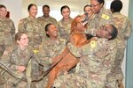 Oliver, a hound dog, plays with several animal care specialists at the U.S. Army Medical Department Center and School Veterinary Training Center, Animal Health Branch, at Joint Base San Antonio-Fort Sam Houston. Oliver is one of several retiring government-owned animals, dogs and cats, who are being put up for adoption so they can be placed in a new home.