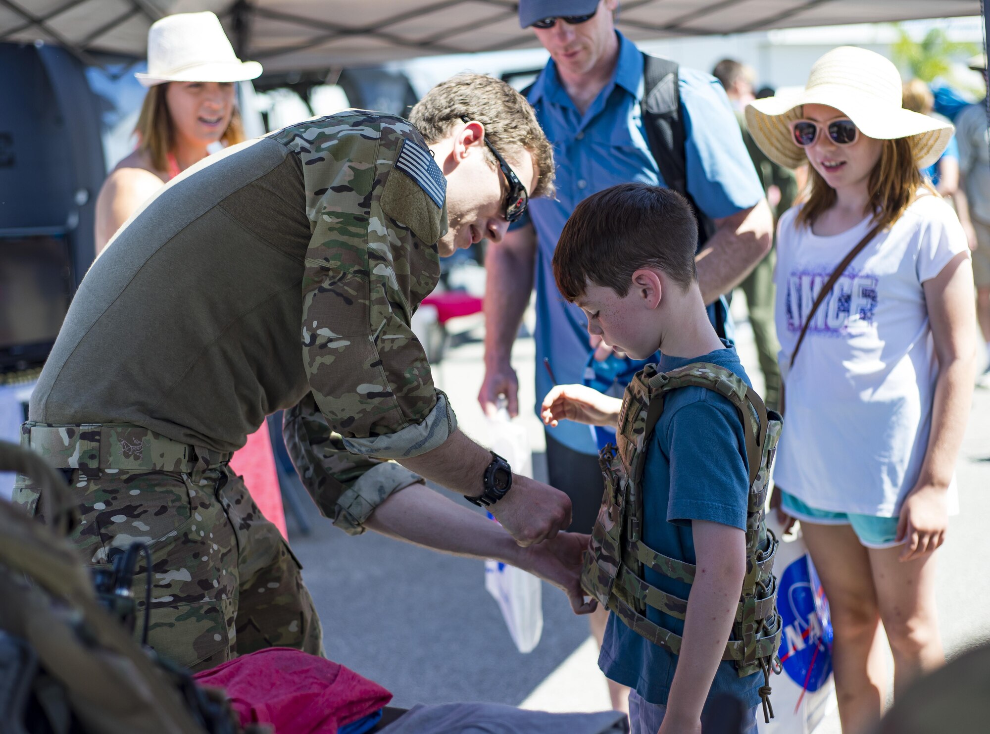 Staff Sgt. Steven Reibitz, a pararescueman from the 308th Rescue Squadron, helps a visitor into a custom body armor plate during the Melbourne Air & Space Show April 1, 2017, at Melbourne, Fla. Airmen from the 920th Rescue Wing displayed the helicopter and equipment used to accomplish the combat search-and-rescue mission. The airshow attracted nearly 200,000 participants and showcased both military and civilian aircraft. (U.S. Air Force photo/Staff Sgt. Jared Trimarchi) 