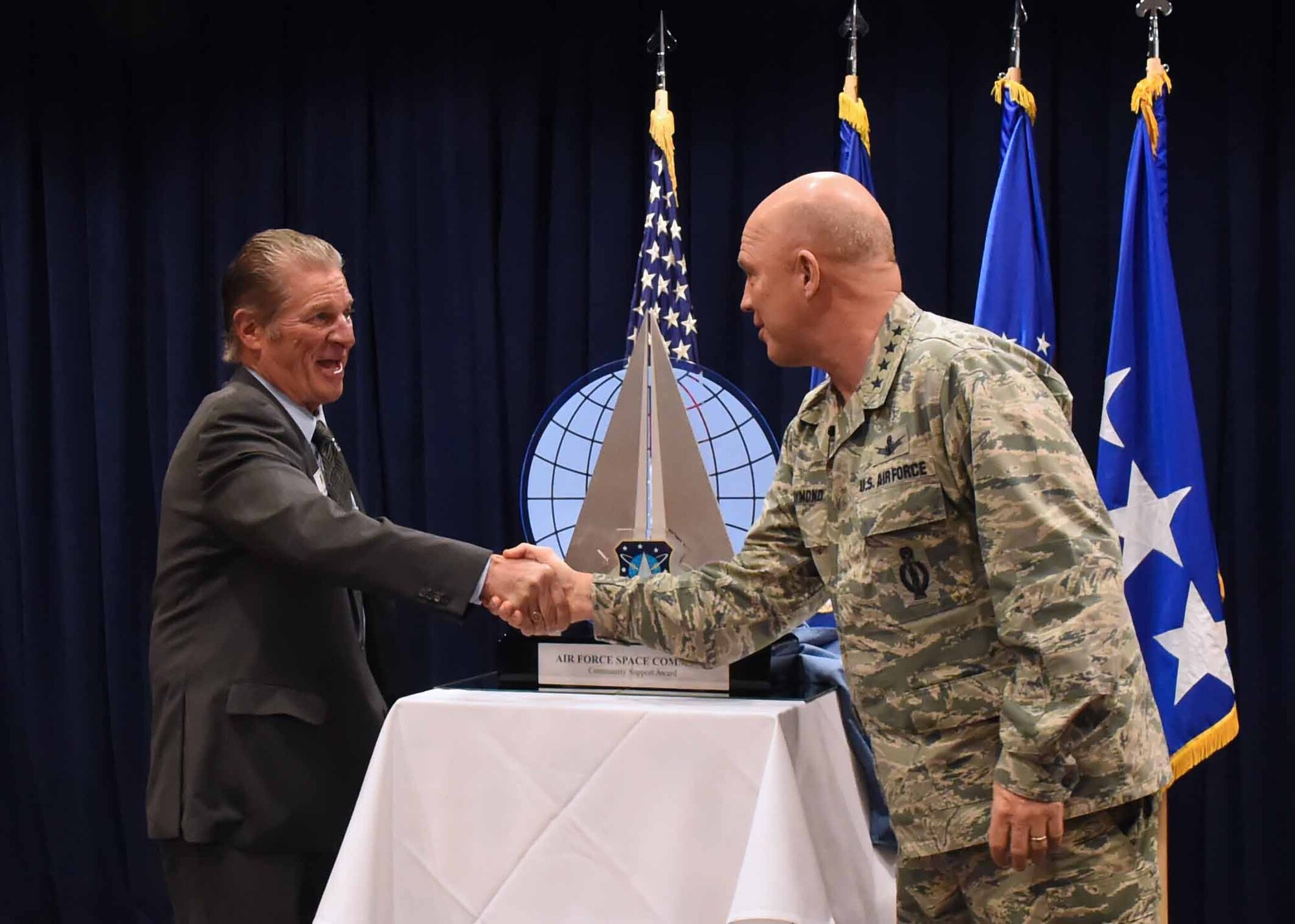 U.S. Air Force Gen. Jay Raymond, Commander, Air Force Space Command, shakes hands with Mr. Michael Jackson of the South Bay Association of Chambers of Commerce, during a ceremony to present the 2016 Air Force Space Command Community Support Award in El Segundo, Calif., Feb. 15, 2017.  The SBACC was named the recipient of the 2016 Air Force Space Command Community Support Award for their outstanding support to the mission and personnel of SMC and Los Angeles Air Force Base. (U.S. Air Force photo by Sarah Corrice)