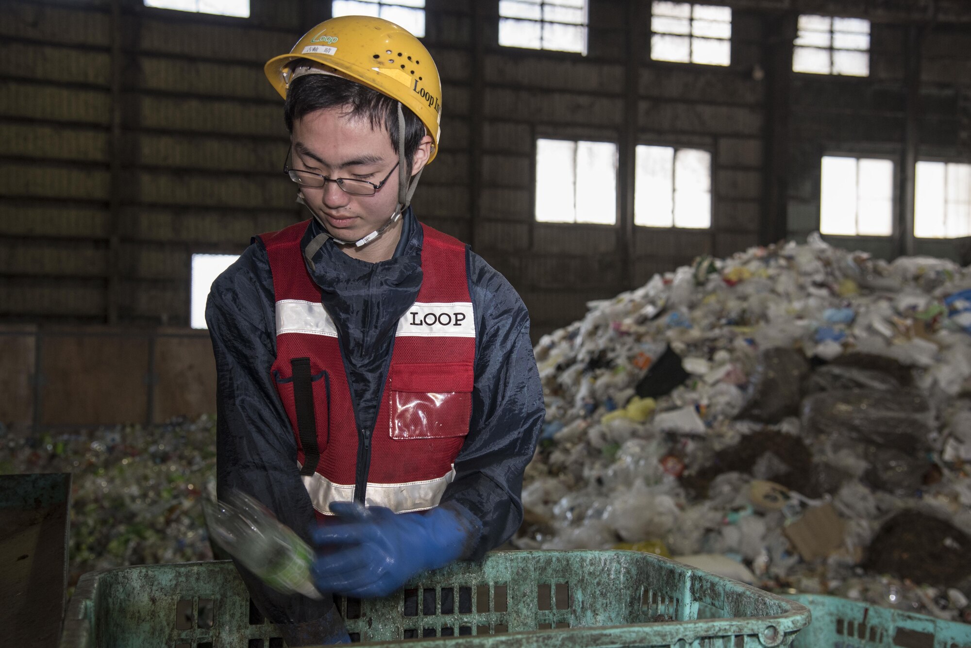 Haru Furujika, a recycling center trash sorter, throws a plastic bottle onto a conveyor belt at Misawa City, Japan, March 20, 2017. Japan’s recycling law is in affect to assist in providing the country with materials. (U.S. Air Force photo by Airman 1st Class Sadie Colbert)