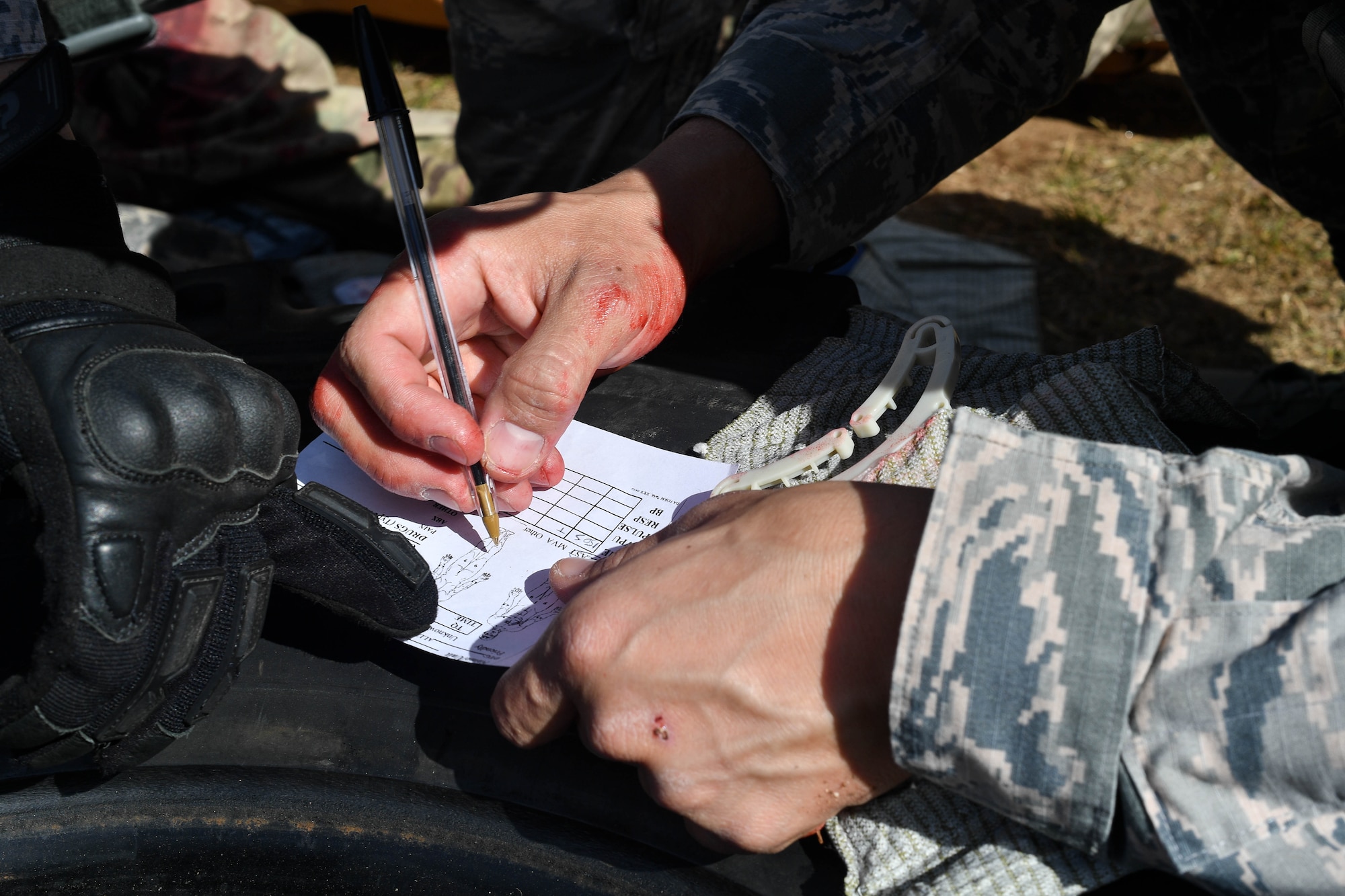 Tech. Sgt. Christian Gomez, 569th U.S. Forces Police Squadron Bravo Flight chief, writes down the injuries of a simulated injured Airman during the tactical combat casualty care portion of 435th Security Forces Squadron’s Ground Combat Readiness Training Center’s Security Operations Course on Ramstein Air Base, Germany, March 30, 2017. During the TCCC portion, the students had to work together to secure the area, provide aid to the simulated victim, call for a medical evacuation, move the victim on to a litter, and load them into a simulated helicopter. Airmen assigned to the 86th SFS, 422nd SFS, 100th SFS, and 569th USFPS participated in the course. (U.S. Air Force photo by Senior Airman Tryphena Mayhugh)