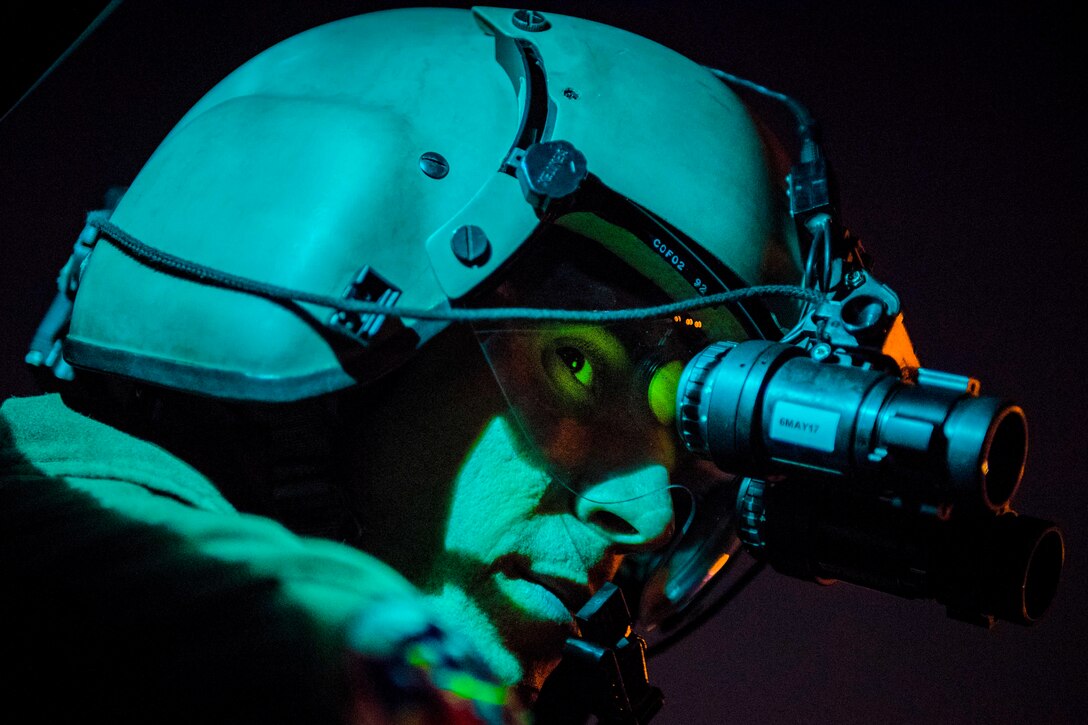 Air Force Staff Sgt. Nicholas A. Poe uses night-vision goggles to look out the window of a UH-N1 helicopter during a night-hoist training exercise at Yokota Air Base, Japan, April 4, 2017. Poe is a special missions aviator assigned to the 459th Airlift Squadron. Air Force photo by Airman 1st Class Donald Hudson