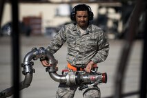 U.S. Air Force Airman 1st Class Braxton Quinlan, 52nd Logistics Readiness Squadron fuels distributor operator, carries a fuel hose after fueling an F-16 Fighting Falcon at Spangdahlem Air Base, Germany, March 28, 2017. “Hot pits” are a more efficient refueling method because the aircraft is refueled with its engines on, making the refill approximately 30% faster. (U.S. Air Force photo by Airman 1st Class Preston Cherry)