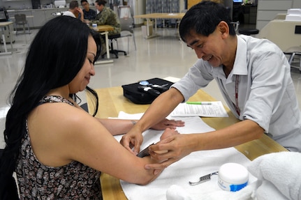 Narciso Sorio (right), certified occupational therapy assistant, performs soft tissue mobilization techniques on patient Irma Olivas in the BAMC Outpatient Occupational Therapy Clinic March 23. An occupational therapist uses these specialized techniques in an effort to help individuals get back to participating in everyday, meaningful activities.