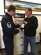 Mr. Brad Boland (right), President O-Neill Transfer and Storage Co., hands off a bottle of 1945 Calvados brandy to Master Sgt. Todd Wivell, 62nd Airlift Wing chief of public affairs, March 5, 2017 at the O-Neill business office in Beaverton, Oregon. Boland, along with other members from the east coast to the west coast, assisted in transporting two separate bottles of this brandy in order to help two World War II veterans complete a pact to toast their fallen comrades. (Courtesy photo
