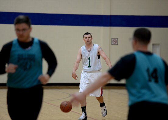 U.S. Air Force Capt. David Cisek, 97th Air Mobility Wing area defense council, dribbles a ball across the court during the championship game, April 4, 2017, at Altus Air Force Base, Oklahoma. The Fitness Center offers several sports throughout the year as a way to support Airmen morale and comradery. (U.S. Air Force Photo by Airman 1st Class Jackson N. Haddon/Released).