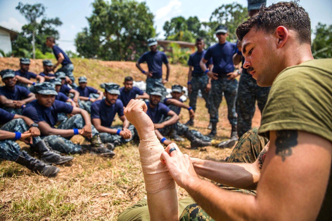 U.S. Navy Petty Officer 3rd Class Ryan Walker, foreground, demonstrates to Sri Lankan Marines the proper way to apply a dressing to a wound during the tactical casualty combat care portion of a military tactics training and exchange, part of a theater security cooperation engagement at Welissara Naval Base, Sri Lanka, March 29, 2017. Walker is a hospital corpsman assigned to 1st Battalion Landing Team, 4th Marines, 11th Marine Expeditionary Unit. Marine Corps photo by Cpl. Devan K. Gowans