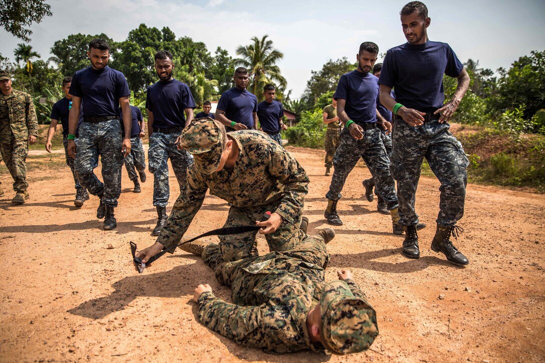 A U.S. Marine demonstrates to Sri Lankan Marines the proper way to apply a tourniquet to a mock patient during the tactical casualty combat care portion of a military tactics training and exchange, part of a theater security cooperation engagement at Welissara Naval Base, Sri Lanka, March 29, 2017. Marine Corps photo by Cpl. Devan K. Gowans