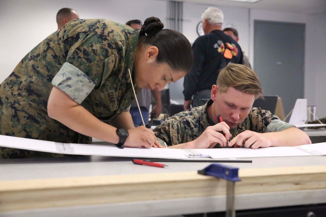 Petty Officer 2nd Class Leyla Coba, cryptologic technician technical, and Cpl. Dylan Lemaistre, signals intelligence and electronic warfare, Tactical Training Exercise Control Group, carve out the wing of a drone at the Fabrication Laboratory aboard Marine Corps Air Ground Combat Center, Twentynine Palms, Calif., March 29, 2017. The newly established FabLab is the first of its kind in the Marine Corps and will provide Marines and sailors the opportunity to develop avant-garde solutions to common problems through utilizing 3D printing technology. (U.S. Marine Corps photo by Cpl. Medina Ayala-Lo)