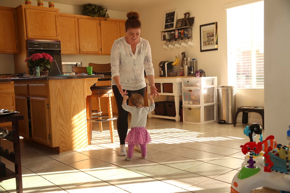 Jessica Rudd, Armed Forces Insurance Marine Spouse of the Year 2017 presented by Military Spouse Magazine, helps her youngest daughter, Molly, 10 months old, stand up at their home in Yucca Valley, Calif., March 29, 2017. Rudd, a Marine veteran, wife and mother of three, was chosen as the 2017 MSOY for her dedication to helping improve the quality of life of military members and their spouses. (U.S. Marine Corps photo by Cpl. Medina Ayala-Lo)