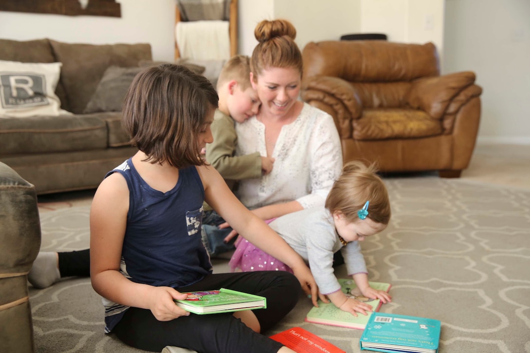 Aubrey Rudd, 7 years old, daughter of Jessica Rudd, Armed Forces Insurance Marine Spouse of the Year 2017 presented by Military Spouse Magazine, choses a book to read to her little sister Molly, 10 months old, at their home in Yucca Valley, Calif., March 29, 2017. Jessica, a Marine veteran, wife and mother of three, was chosen as the 2017 MSOY for her dedication to helping improve the quality of life of military members and their spouses. (U.S. Marine Corps photo by Cpl. Medina Ayala-Lo)