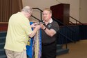 Members of the 307th Bomb Wing alumni groups attached streamers to the 307th Maintenance Squadron&#39;s guidon representing awards received during World War II, the Korean War, Vietnam and the Cold War during the 75th Anniversary Celebration. 