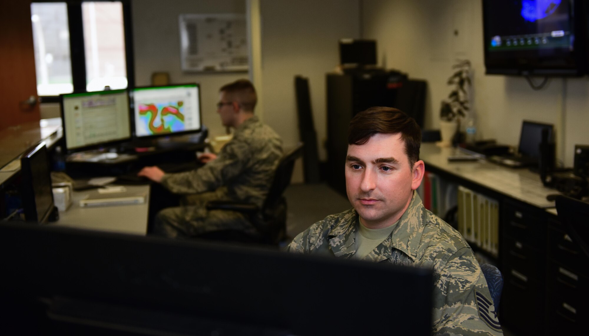 U.S. Air Force Tech. Sgt. Jon Stimmel Jr., right, the 509th Operations Support Squadron (OSS) NCO in charge of mission weather operations, develops a flying brief while Senior Airman Alex Knowles, left, a weather forecaster assigned to the 509th OSS, reviews the base forecast at Whiteman Air Force Base, Mo., March 28, 2017. The shop is divided into the mission operations and airfield operations sections, as well as a training. (U.S. Air Force photo by Airman 1st Class Jazmin Smith)