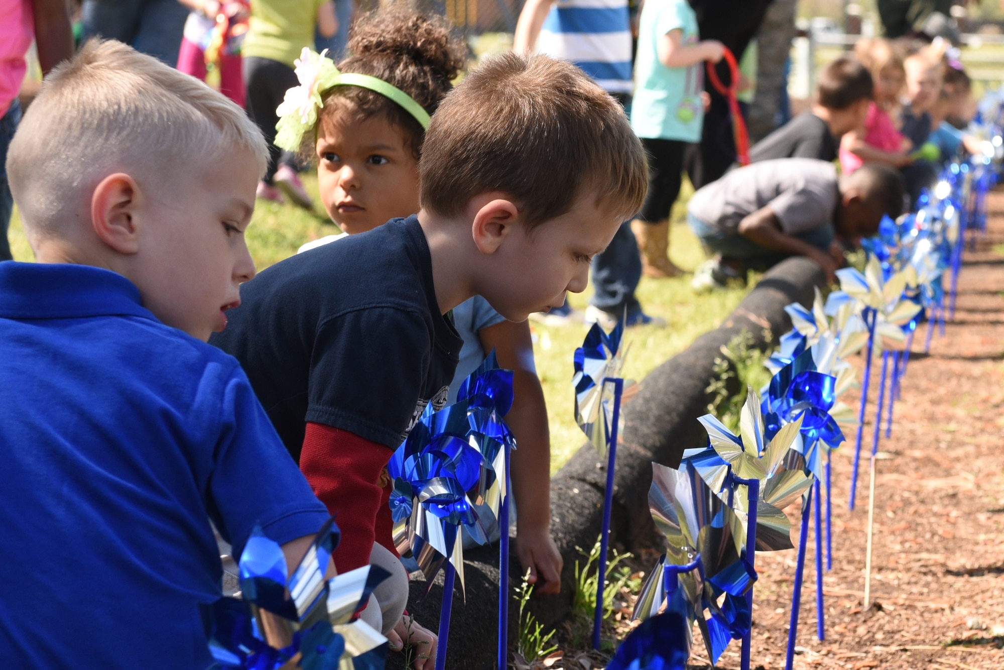 Children from the Seymour Johnson Air Force Base 4th Force Support Squadron Child Development Center “plant” pinwheels around the perimeter of a playground, April 4, 2017, at Seymour Johnson Air Force Base, North Carolina. The children helped set up more than 80 pinwheels at the CDC to raise awareness of Child Abuse Prevention Month. (U.S. Air Force photo by Airman 1st Class Victoria Boyton)
