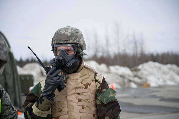 U.S. Air Force Airman 1st Class Cayden Riddle, a 354th Civil Engineer Squadron pavement and construction equipment operator, listens to his walkie-talkie during chemical warfare training for exercise Arctic Gold 17-5 April 6, 2017, at Spruce Lake on Eielson Air Force Base, Alaska. During this portion of the training, only a select few Airmen were allowed to go outside their simulated bunkers to do precision approach radar sweeps. (U.S. Air Force photo by Airman 1st Class Isaac Johnson)