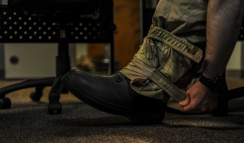 Capt. John Tobin, an electronic warfare officer with the 15th Special Operations Squadron, fastens his Chemical Protective Overgarment trousers to his boots during a chemical, biological, radiological and nuclear survival skills class at Hurlburt Field, Fla., April 4, 2017. The defense classes teaches Air Commandos how to properly don the CPO in case of a chemical warfare related attack. (U.S. Air Force photo by Airman 1st Class Isaac O. Guest IV)