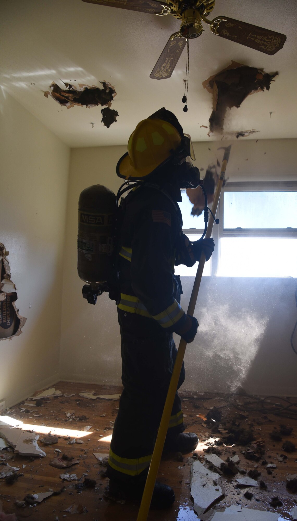 A 22nd Civil Engineer Squadron firefighter performs overhaul and salvage during a training exercise April 6, 2017, in base housing at McConnell Air Force Base, Kan. This procedure is used to look for fire extension into the walls or ceiling of a building. (U.S. Air Force photo/Airman 1st Class Erin McClellan)