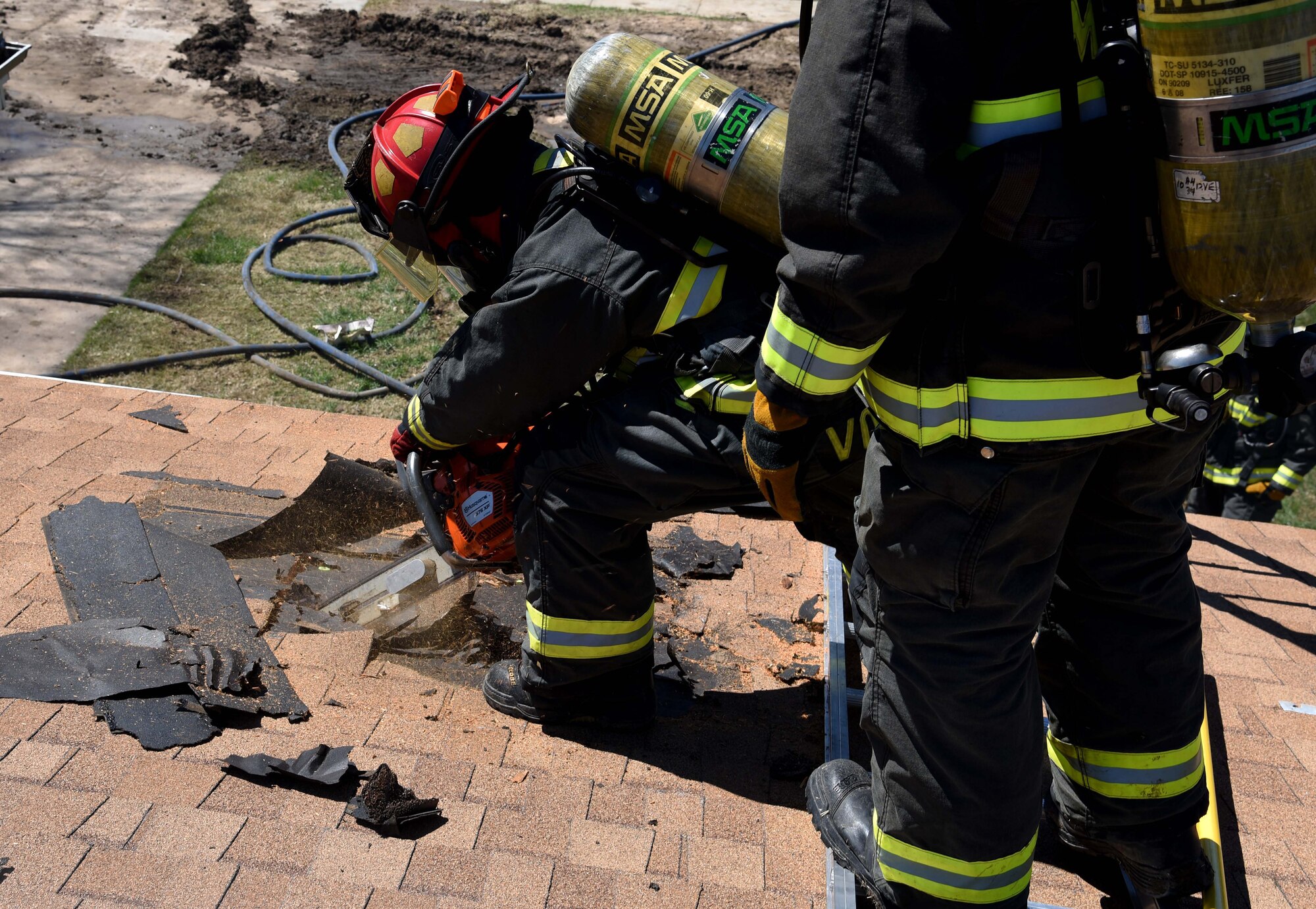 Brad Voorhees, 22nd Civil Engineer Squadron lead firefighter, uses a chainsaw to cut a hole in the roof of a vacant house during a training exercise April 6, 2017, in base housing at McConnell Air Force Base, Kan. Vertical ventilation is a method used during structural firefighting. (U.S. Air Force photo/Airman 1st Class Erin McClellan)