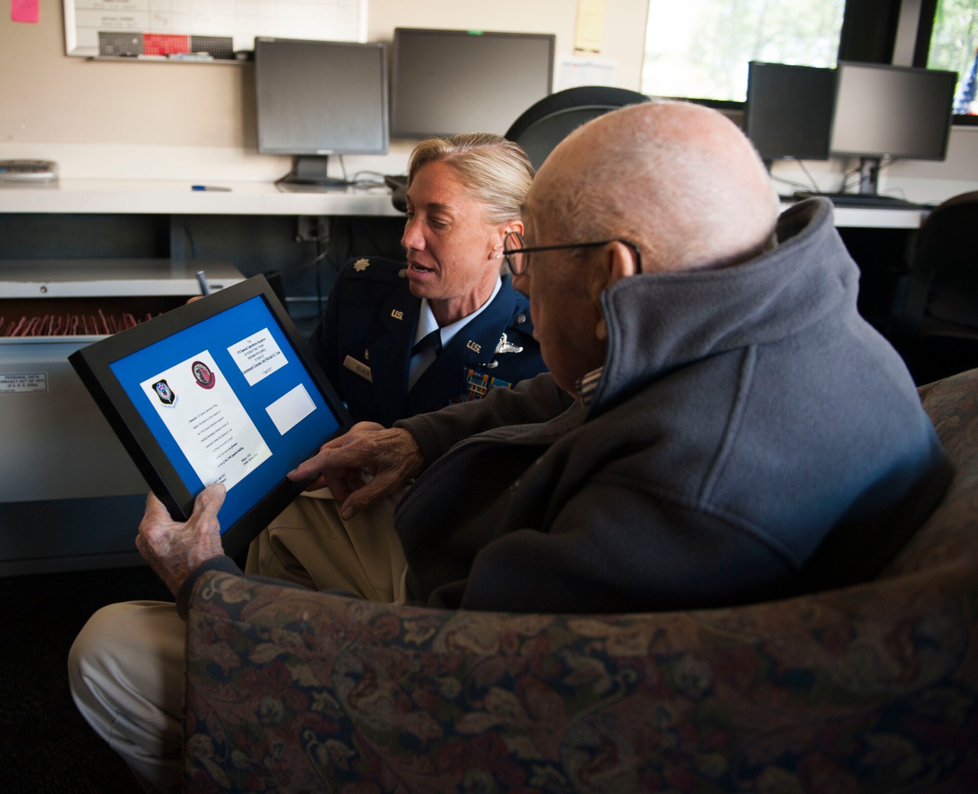 Lt. Col. Allison Black, commander of the 319th Special Operation Squadron, shows retired Lt. Col. Richard E. Cole a framed invitation after a building renaming and dedication ceremony at Hurlburt Field, Fla., April 7, 2017. Cole is the last surviving Doolittle Raider whose Air Force roots date back to the origination of the 319th SOS. (U.S. Air Force photo by Senior Airman Krystal M. Garrett)