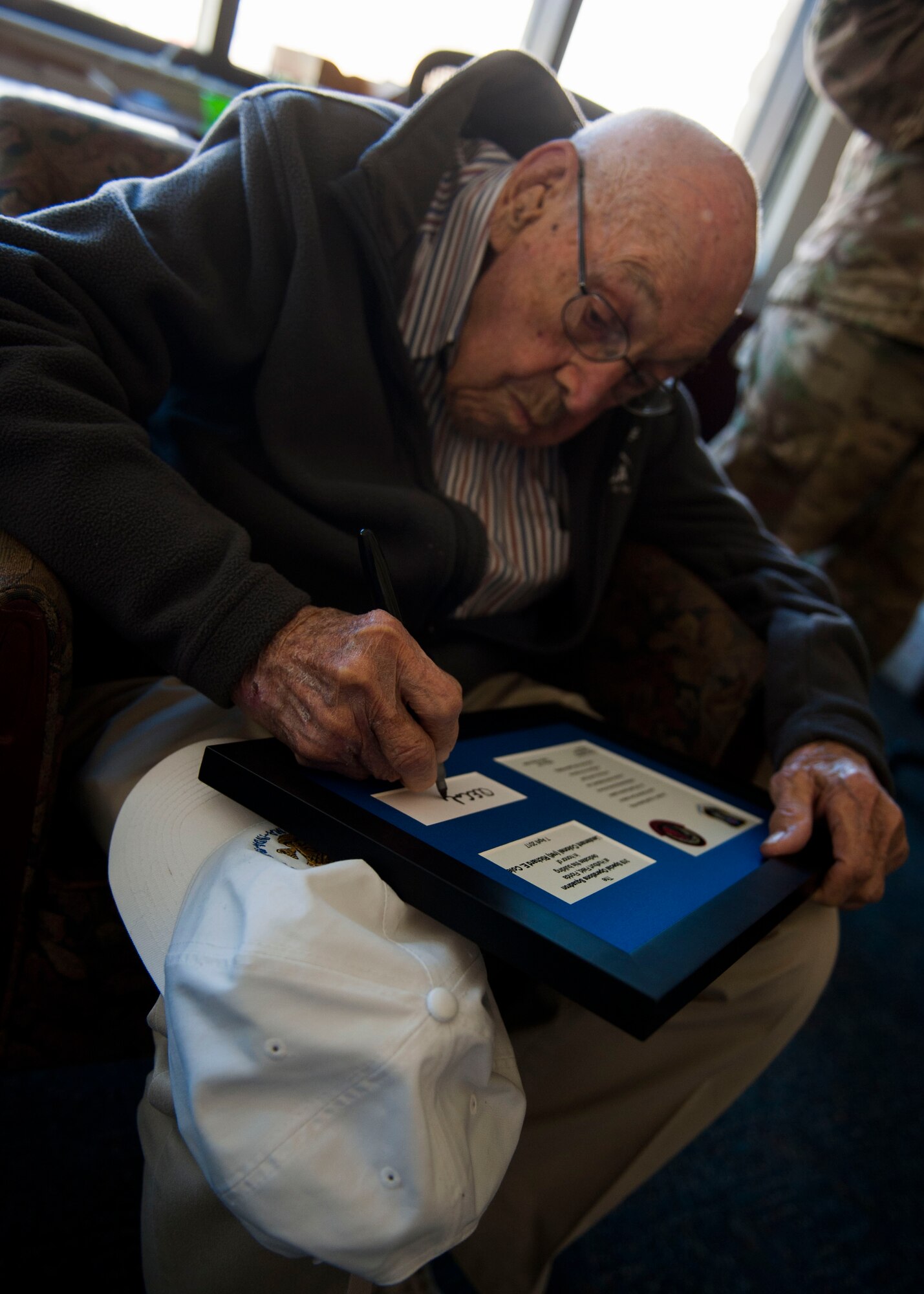 Retired Lt. Col. Richard E. Cole signs a framed invitation during a building renaming and dedication ceremony at Hurlburt Field, Fla., April 7, 2017. The 319th Special Operations Squadron building was renamed after Cole in honor of his career as an early Air Commando and Doolittle Raider. (U.S. Air Force photo by Senior Airman Krystal M. Garret)