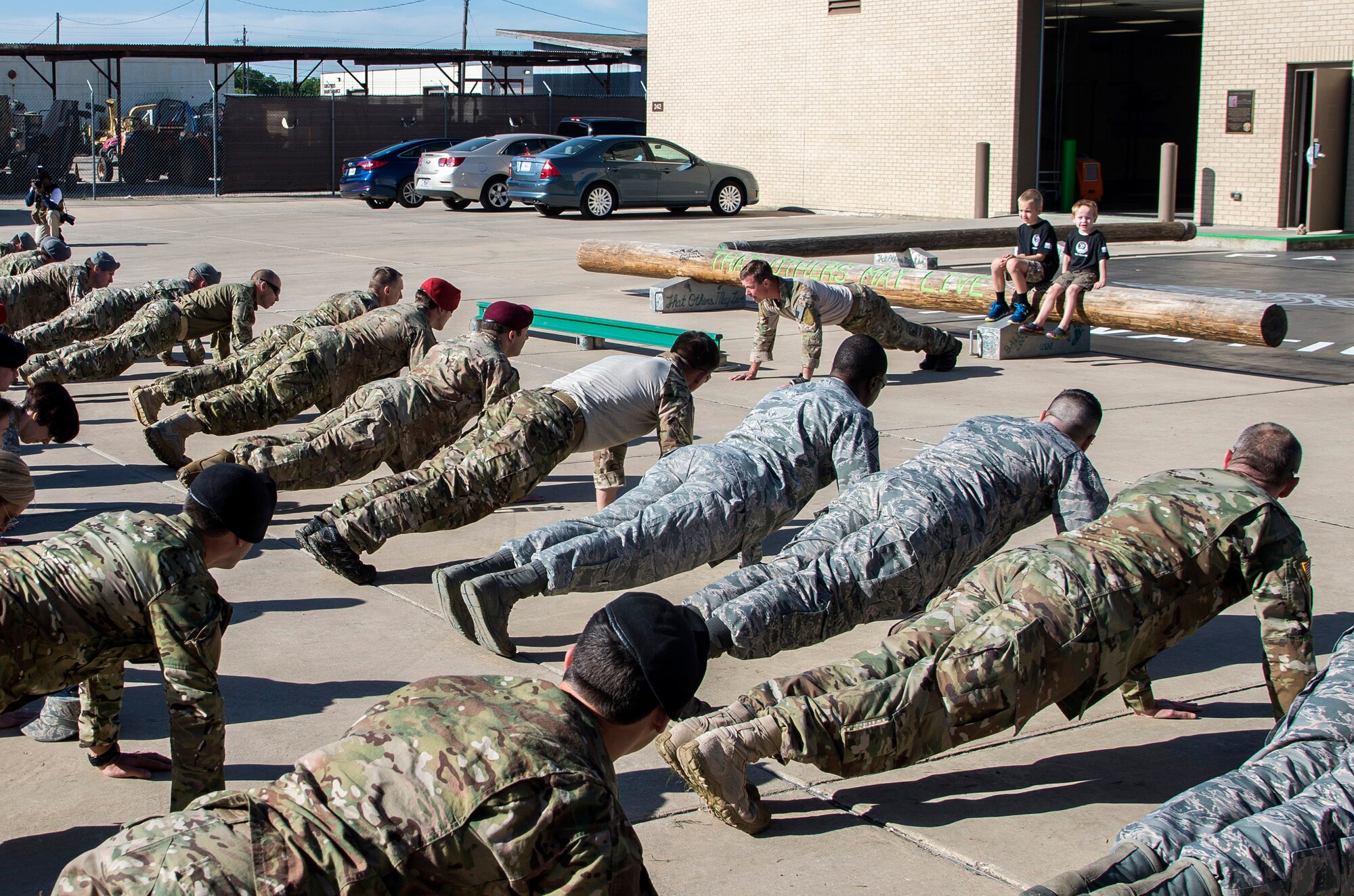 Members of the 350th Battlefield Airmen Training Squadron and from throughout Joint Base San Antonio-Lackland perform “memorial push-ups” during a memorial remembrance ceremony honoring Lt. Col. William “Bill” Schroeder while his two sons observe April 7, 2017, at JBSA-Lackland, Texas, Medina Annex. Schroeder’s unit honored his legacy renaming a drop zone as Schroeder DZ and participated in a "Monster Mash" fitness competition, remembrance ceremony and log march. April 8, 2016, Schroeder recognized a perilous situation developing and reacted swiftly by putting himself between an armed individual and his first sergeant. In the process, he saved lives of other squadron members while being fatally wounded. Schroeder was posthumously awarded the Airman’s Medal, given to those that distinguish themselves by a heroic act – usually at the volunteer risk of their lives but not involving combat. (U.S. Air Force photo by Johnny Saldivar)