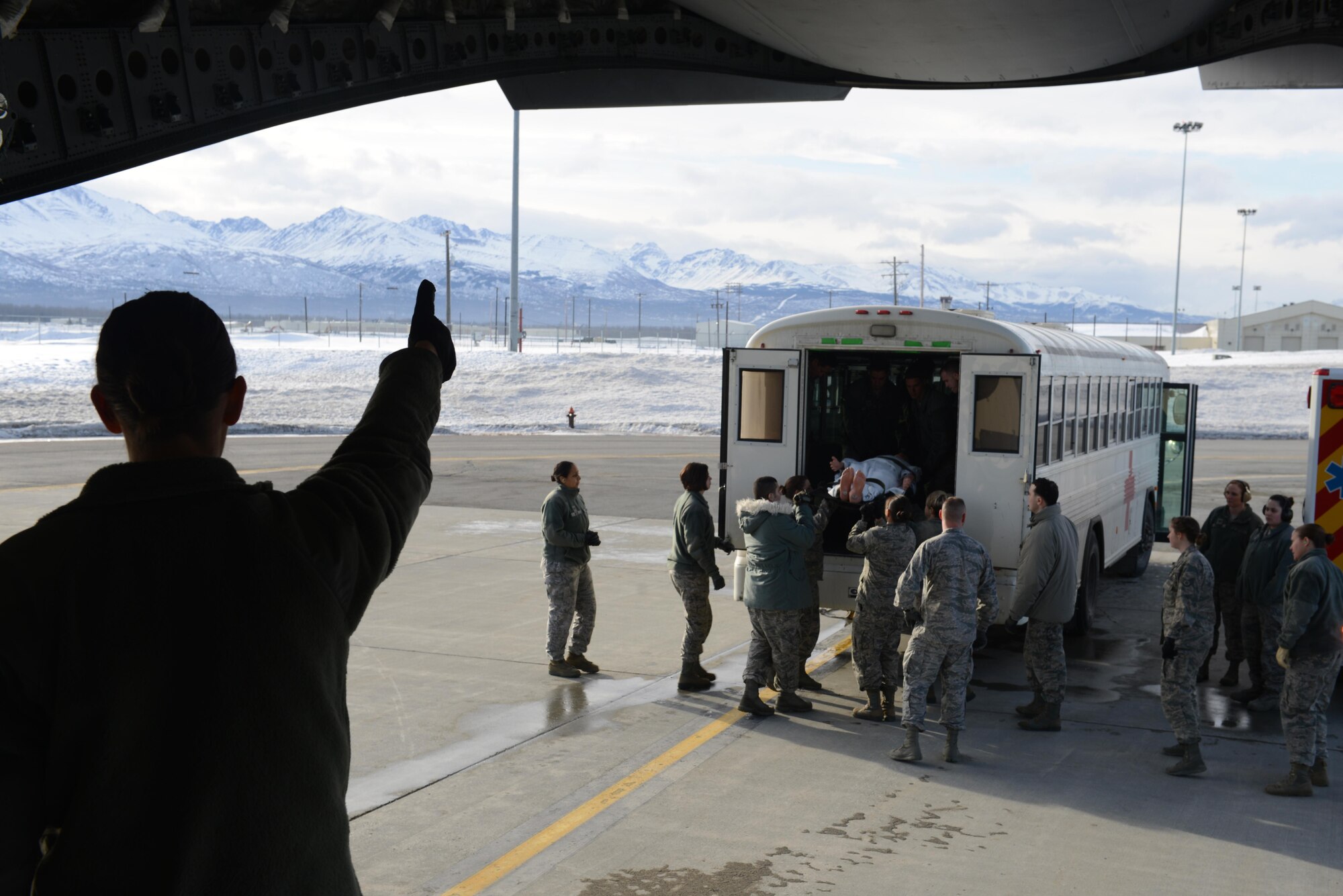 U.S. Air Force Capt. Leslie Mead, 673d Medical Group, gives the signal for the next simulated patient to be transported into a C-17 Globemaster III during the EnRoute Patient Staging System exercise at Joint Base Elmendorf-Richardson, Alaska, April 3, 2017. The ERPSS provides patient reception, limited emergent intervention, and ensures patients are medically and administratively prepared for flight in a safe and timely aeromedical evacuation. 