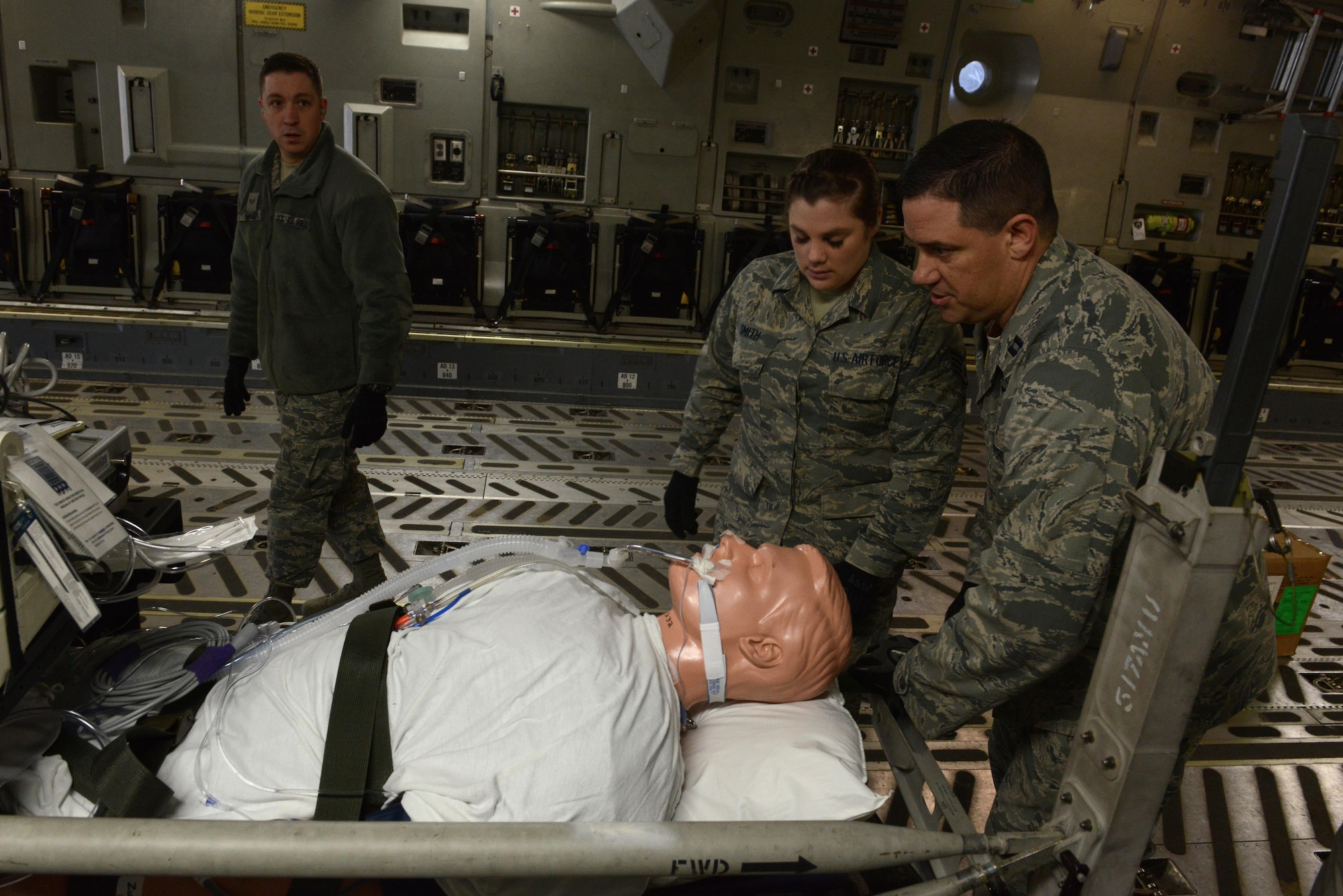 U.S. Air Force Capt. Paul Padilla (right) and Staff Sgt. Tiffany Smith (center) secure a simulated patient in a C-17 Globemaster III during the EnRoute Patient Staging System exercise at Joint Base Elmendorf-Richardson, Alaska, April 3, 2017. The ERPSS provides patient reception and limited emergent intervention, and ensures patients are medically and administratively prepared for flight in a safe and timely aeromedical evacuation. 